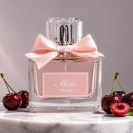 بطری عطر میسیس چری روونا با روبان صورتی، در استودیوی عکاسی و احاطه‌شده با دانه‌های گیلاس تازه