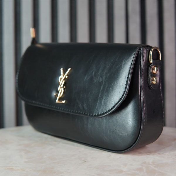 کیف زنانه YSL مشکی با طراحی مینیمال و لوگوی فلزی طلایی، نمای سه‌رخ روی پس‌زمینه استودیویی خاکستری